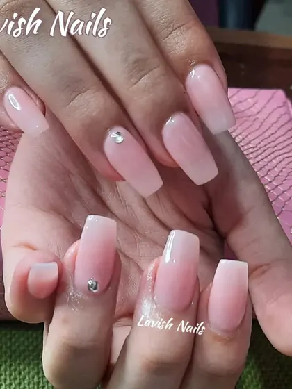 A beautiful set of sheer pink, coffin-shaped nails with a jelly-like finish, accented with a single rhinestone for a touch of minimalist elegance.