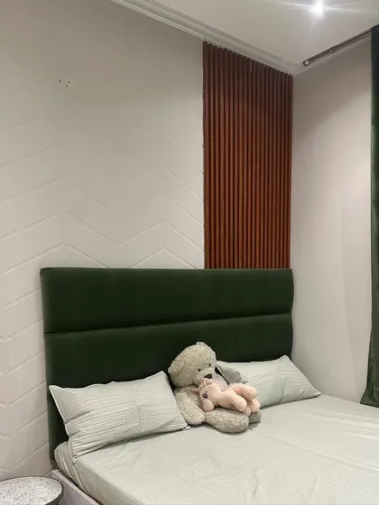 The wall behind the bed features a combination of textured white panels and vertical wooden fluting, adding depth and interest to this guest room.