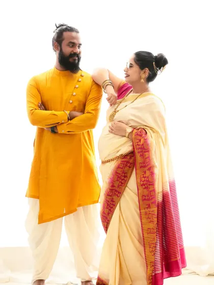 A beautiful portrait celebrating tradition. The mom-to-be wears an elegant off-white and pink saree, while her partner complements her in a yellow kurta, creating a vibrant and culturally rich image.