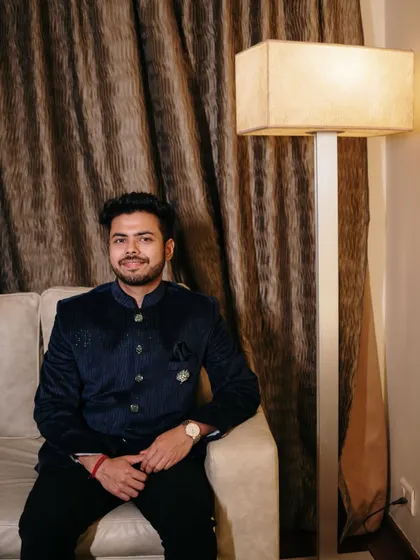 A dapper portrait of the groom looking sharp in his navy blue bandhgala, patiently waiting for the engagement festivities to begin.