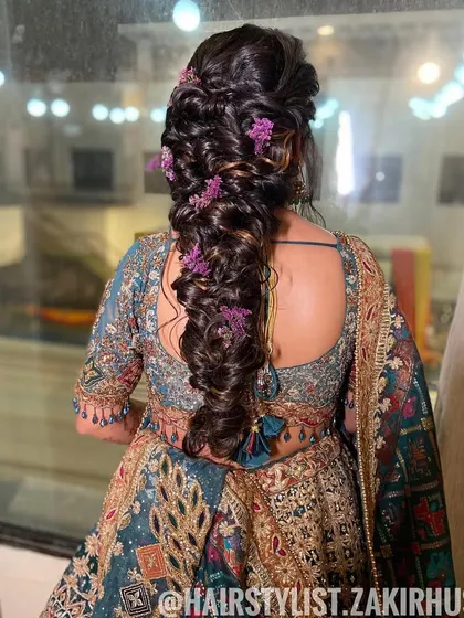 A voluminous bubble braid with purple flowers tucked in. This is a beautiful and modern hairstyle for a bride who wants something unique for her wedding day.