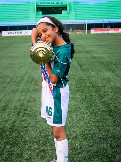 A future star with her prize. A young player from our U13 girls' team holds her championship trophy, a cherished memory from a successful tournament.