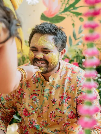 A close-up of the groom having turmeric applied, a moment of blessing and fun shared with loved ones.