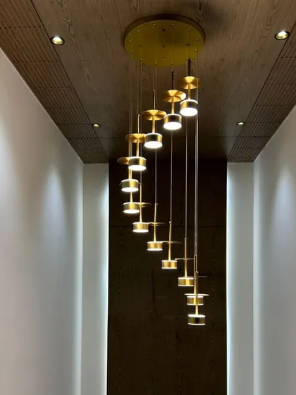 A full view of the spiral chandelier in a hallway with a wooden ceiling, creating a dramatic and elegant effect.