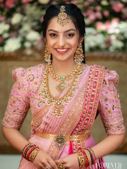 A closer look at the hand-embroidered puff-sleeve blouse designed to complement the Kanchi lehenga. The delicate floral embroidery on the blouse echoes the richness of the saree, creating a cohesive and personalized bridal ensemble.