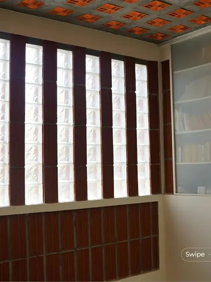 A study or library space in the Manjunath Residence, featuring walls of glass blocks and terracotta that allow for diffused natural light, perfect for reading.