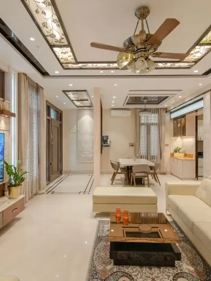 A wider view of the living area, showing the custom ceiling with stained glass panels and the travertine marble TV wall.