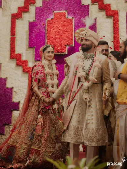 The couple walks hand-in-hand, a picture of unity and happiness. The grand floral backdrop adds a vibrant, celebratory feel to this candid moment during the ceremony.