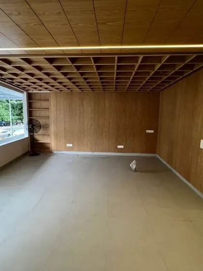 This is the welcome space for an institute in Koramangala, nearing completion. The extravagant waffle slab ceiling, clad in rich veneer, and the warm strip lighting create an inviting and unique first impression that is visible directly from the main road.