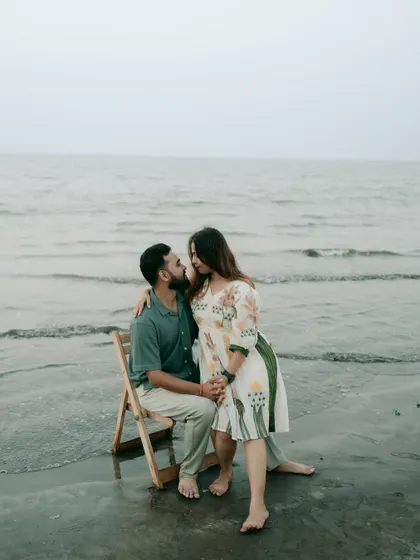 A romantic pose with a chair prop in the water, creating a cinematic feel for this pre-wedding photograph.