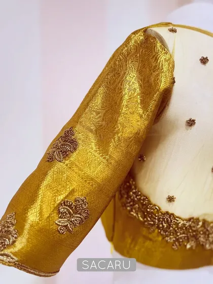 A detailed view of our gold Benarasi blouse, showing the sheer back with scattered butis and the intricately woven fabric of the sleeve.
