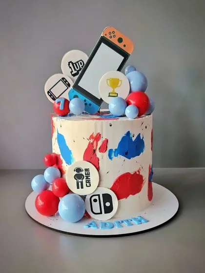For a gamer! A cookies and cream cake with a Nintendo Switch theme, decorated with edible logos and colorful chocolate spheres.