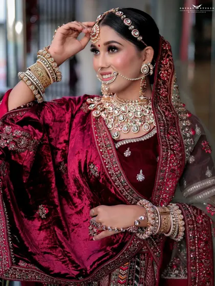 A graceful shot of the bride adjusting her matha patti. This candid-style photo captures a quiet moment, highlighting her elegance and the beauty of her bridal accessories.
