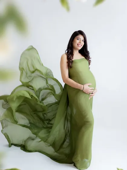 A graceful and artistic portrait. The flowing olive green fabric creates a beautiful sense of movement, highlighting the mom-to-be's elegant pose.