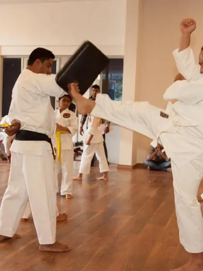 An adult student practicing a powerful kick on a pad. Our classes are for all ages, whether you are a beginner or returning to training.