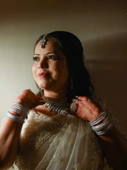 A portrait of the bride looking thoughtfully into the distance, captured with dramatic side lighting. This artistic shot highlights her features and the intricate necklace she is wearing.
