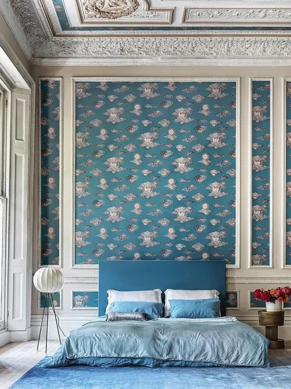 The 'Soli e Nuvole' wallpaper applied in a grand bedroom with high ceilings and ornate mouldings. The deep teal colorway creates a celestial atmosphere, turning the room into a work of art.
