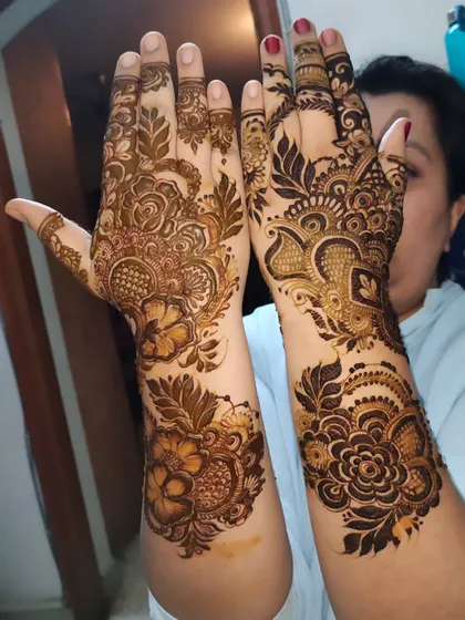 A happy client showing off her intricate mehndi. The design is a beautiful mix of floral and paisley patterns.