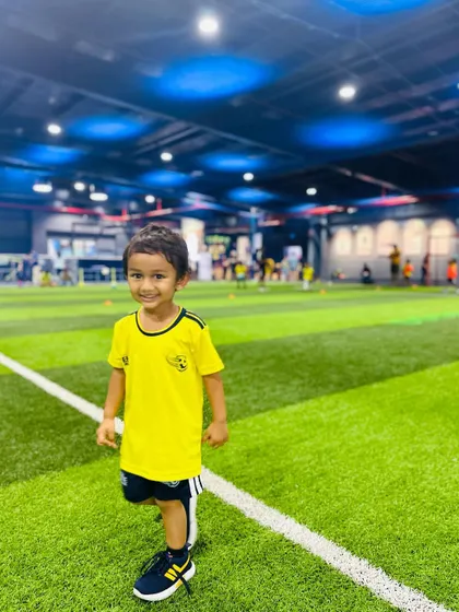 A young player stands proudly on the turf. We aim to build confidence in every child who joins our program.