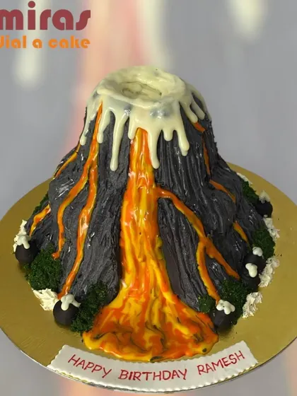 An explosive volcano cake! This sculpted cake is designed to look like an erupting volcano, with orange and yellow "lava" flowing down its sides. It's a thrilling centerpiece for an adventurous birthday.