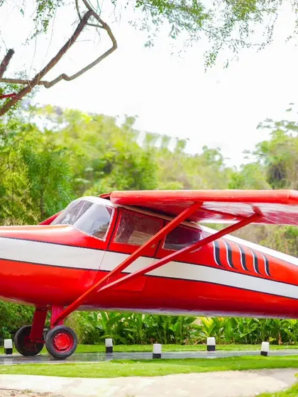 A unique and adventurous maternity shot with a vintage red airplane as the backdrop.