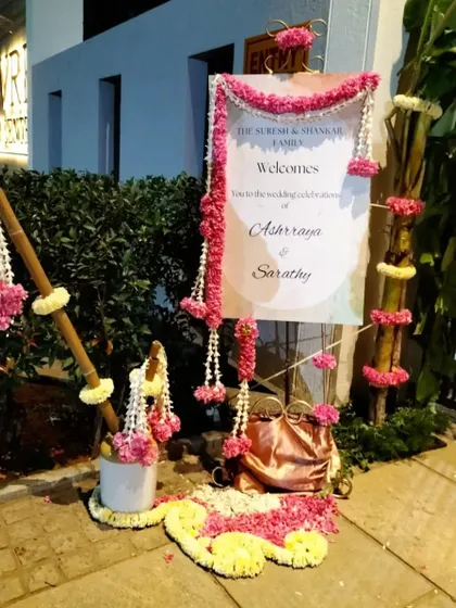 A welcome sign decorated with pink and white floral garlands, creating a traditional and festive entrance for the wedding guests.
