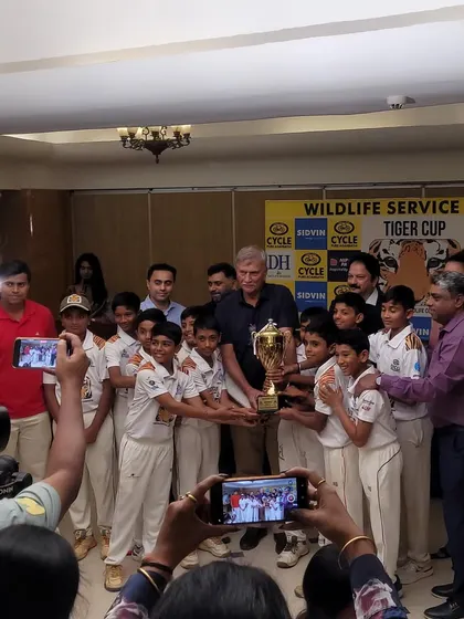 The entire U12 team receiving the prestigious Tiger Cup trophy from the legendary Mr. Roger Binny after a spectacular tournament performance.