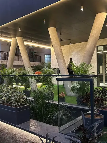 A completed modern rooftop garden featuring large angled support columns and a mix of planters on a raised, illuminated platform.