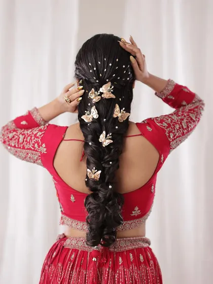 A dreamy and modern braid adorned with gold butterfly clips and scattered pearls. This hairstyle is perfect for a bride who wants a touch of whimsy and elegance.