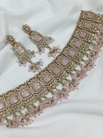 A popular choker design featuring square-cut stones, available in a variety of colors like emerald green, white, aqua blue, and baby pink. The matching earrings complete this elegant and modern ethnic set.
