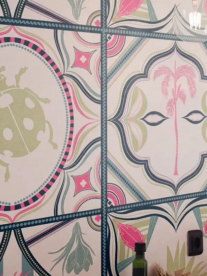 A closer look at the 'Tropical Tapestry' wallpaper. You can see the hand-drawn details in the ladybugs and palm trees, designed to look like individual, colourful tiles that fit together seamlessly.