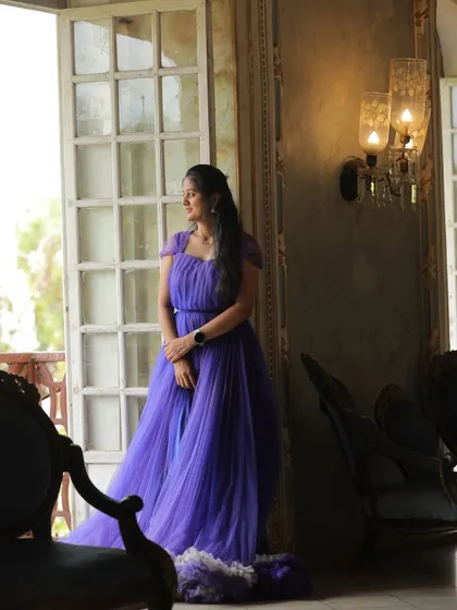 A beautiful solo portrait of the bride-to-be. The soft light from the window highlights the delicate details of the purple ruffled gown.