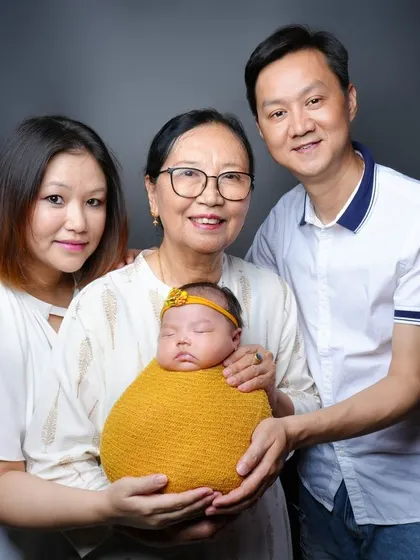 Welcoming the newest member with multiple generations. This portrait includes the baby's grandmother, creating a precious multi-generational family memory.
