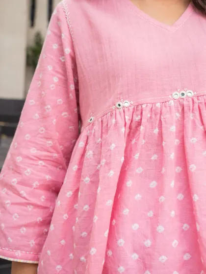 A close-up of the details on our Suhani Bandhej top. The delicate mirror work at the empire line adds a subtle sparkle to the hand-tied patterns, showcasing the thoughtful craftsmanship in every piece.
