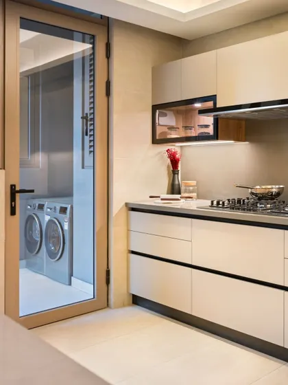 A modern kitchen designed for functionality, featuring handleless cabinets and a dedicated utility area. The clean lines and neutral palette create a space that is both efficient and visually calm.