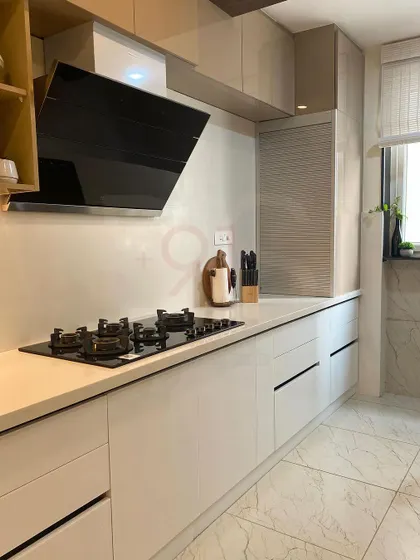 The kitchen is equipped with a modern chimney and hob, set against a clean, white countertop and backsplash.