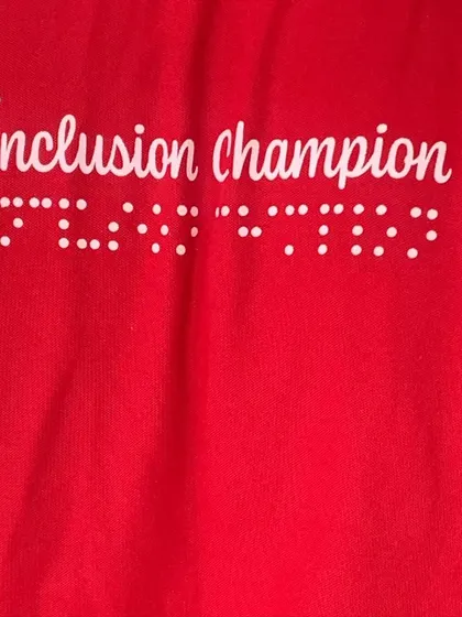 A close-up of the "Inclusion Champion" shirt with braille lettering. This represents the spirit of the work I do with Enable India, promoting accessibility in sports.