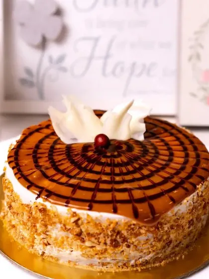 A delicious butterscotch cake with a caramel glaze, chocolate drizzle, and crunchy praline.