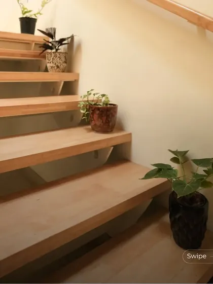 Small potted plants are placed on the steps of the staircase, adding a touch of green and life to the simple, elegant design.