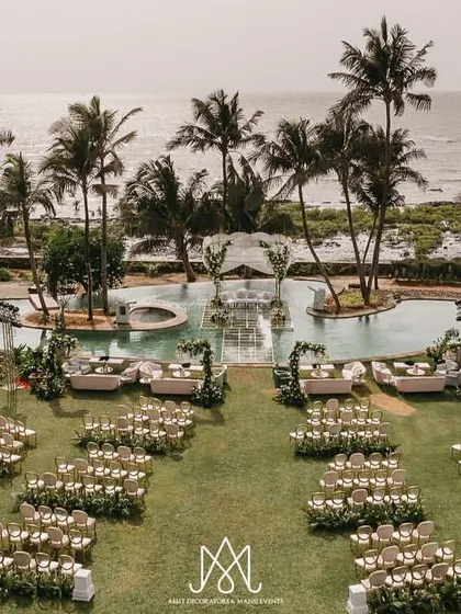 A stunning aerial view of a serene waterside wedding. This shot highlights my expertise in transforming unique venues, featuring a custom aisle built over the pool leading to an elegant mandap.