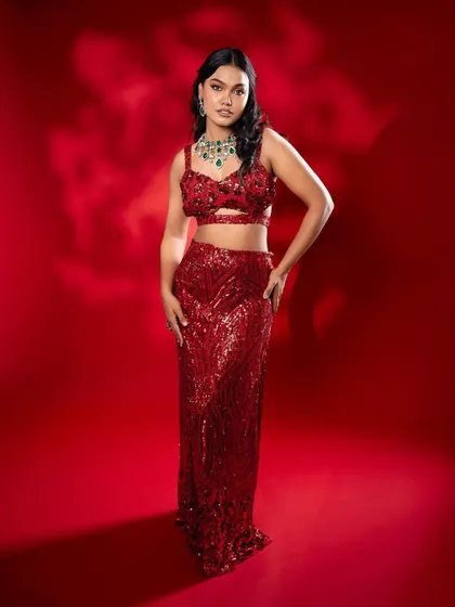 A full-length shot of a model in a stunning, sequined red gown, paired with a modern emerald and diamond necklace. This shows how my jewellery can be styled for western-style reception outfits too.