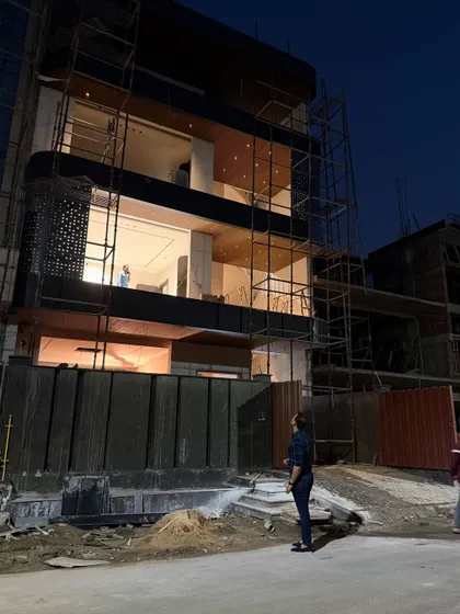 The house in Noida is taking shape. This view shows the contrast between the solid gate and the open, glass-filled floors above.