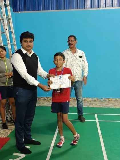 A player from our youth badminton program is presented with his certificate, recognizing his successful completion of the tournament.
