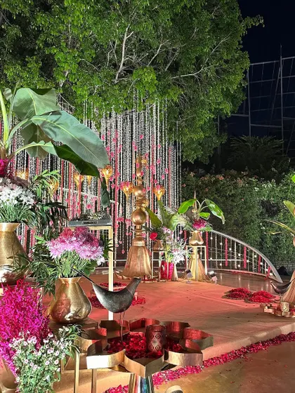 A breathtaking vedi setup for a night wedding, featuring banana leaves, brass elements, and a profusion of pink and white flowers.