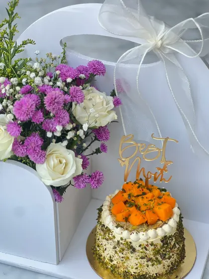 Our special Mother's Day hamper, featuring a fresh mango and pistachio cake paired with a beautiful bouquet of white and purple flowers.