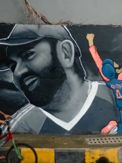 A tribute to Indian cricket captain Rohit Sharma on a public wall in Mumbai. This large-scale realistic portrait captures his likeness in monochrome, contrasted with a smaller, full-color action shot, celebrating a true sports icon.
