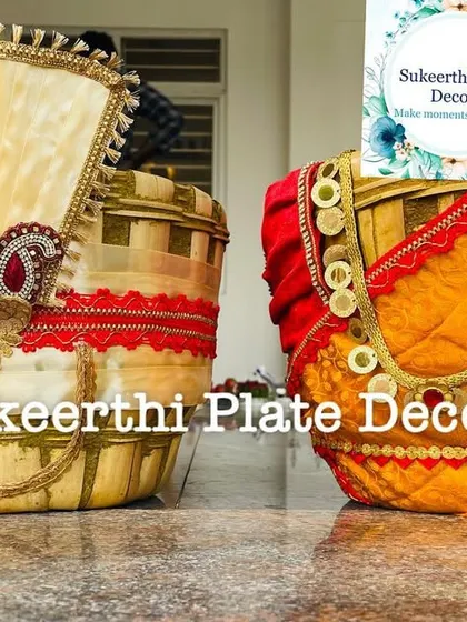 A close-up of a decorated Uppukudai pair, showing the detailed fabric work and the 'kasu malai' style necklace on the bride basket.