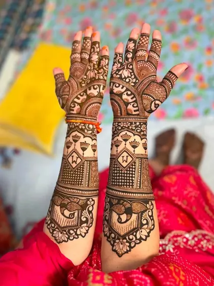 A unique bridal design with the initial 'W' set inside a lotus motif. The peacocks at the bottom add a touch of traditional elegance.