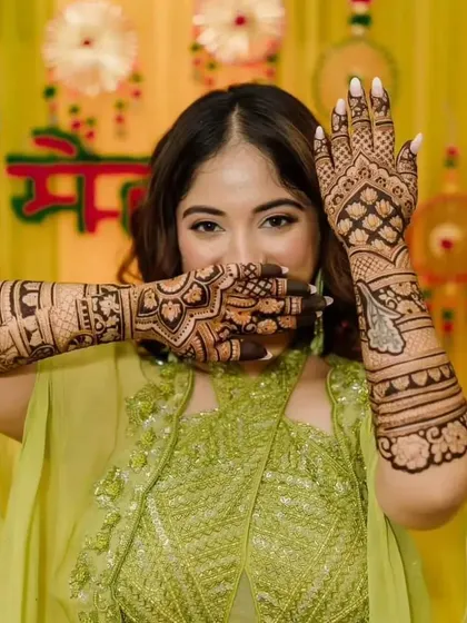 A happy bride posing at her mehendi ceremony, her hands covered in my intricate designs.