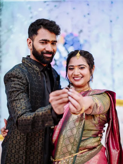 A joyful photo of a couple showing their engagement rings to the camera.